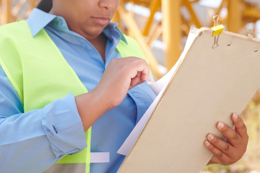 BHV coordinator reviewing a BHV policy plan on a clipboard at a worksite